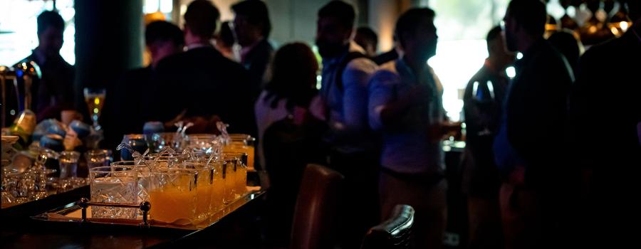 Alcoholic beverages on a bar with silhouettes of people in the background